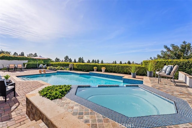 view of swimming pool featuring a pool with connected hot tub and a patio area