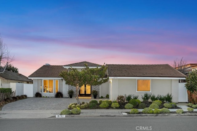 view of front of house with stucco siding, fence, and a tiled roof