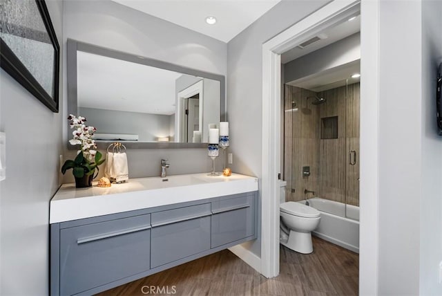 bathroom with toilet, wood finished floors, vanity, washtub / shower combination, and baseboards