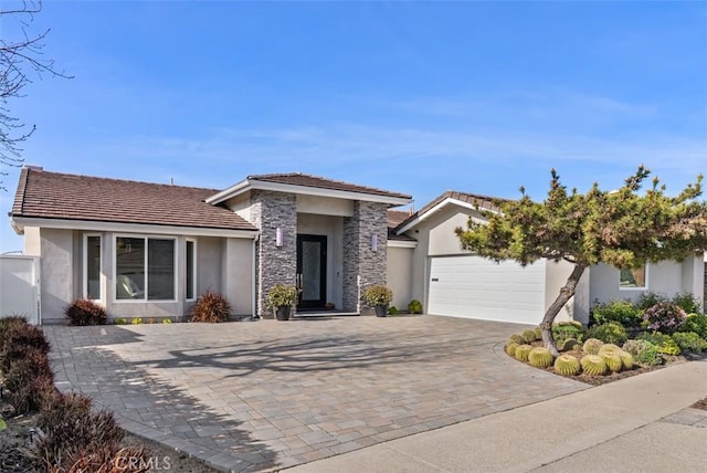 view of front of property featuring stucco siding, a garage, driveway, a tile roof, and stone siding