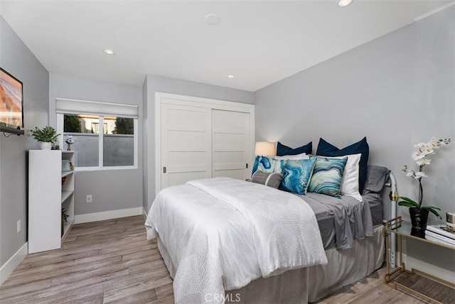 bedroom featuring a closet, light wood finished floors, baseboards, and recessed lighting