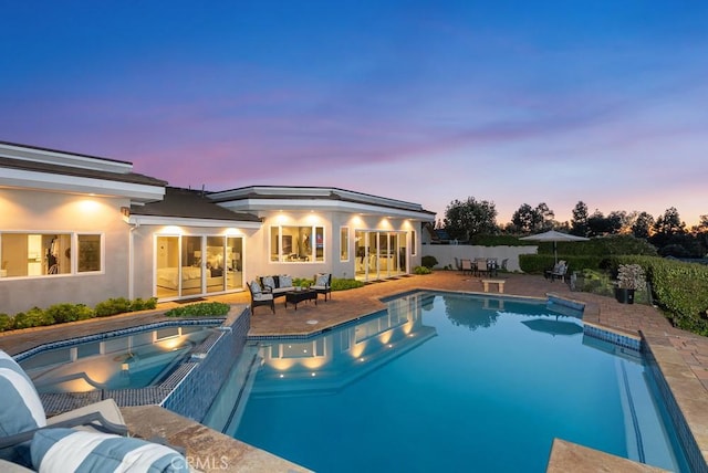 pool at dusk featuring an outdoor hangout area, a patio area, and a pool with connected hot tub