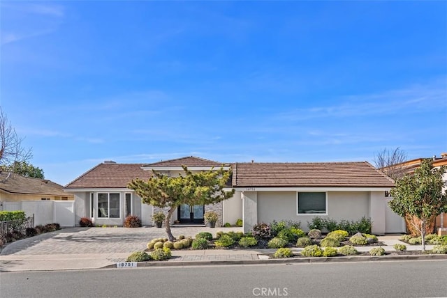view of front of property featuring a tiled roof, fence, and stucco siding