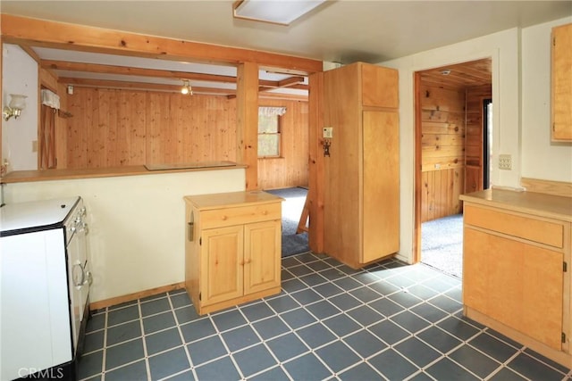 kitchen with light countertops, wooden walls, light brown cabinetry, beamed ceiling, and dark floors