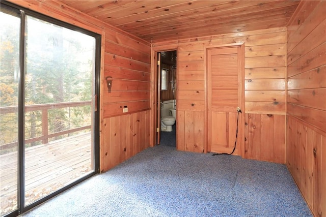 carpeted spare room with wooden ceiling and wood walls
