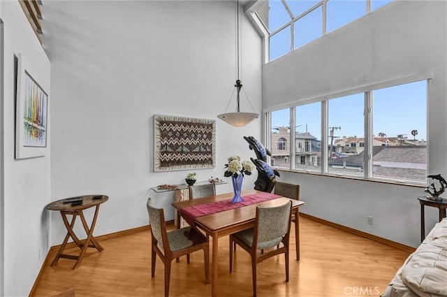 16745 Bayview Dr Unit B, Sunset Beach, CA 90742 - dining room with healthy amount of natural light, light wood-type flooring, a high ceiling, and baseboards