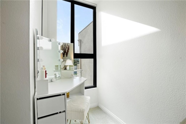interior space with a wealth of natural light, a textured wall, carpet flooring, and baseboards