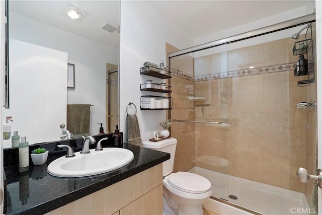 bathroom featuring vanity, toilet, a stall shower, and visible vents