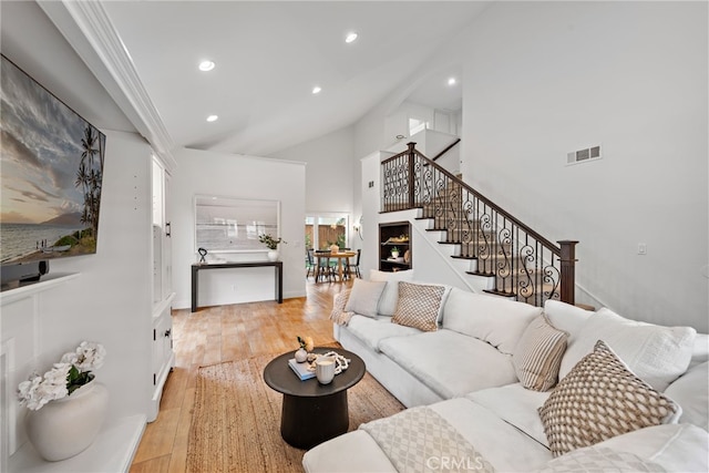living area featuring visible vents, light wood-type flooring, stairway, high vaulted ceiling, and recessed lighting