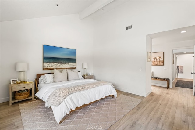 bedroom featuring high vaulted ceiling, baseboards, light wood-style floors, beamed ceiling, and visible vents