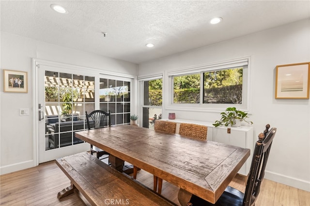 dining room with plenty of natural light, light wood-style floors, and a textured ceiling