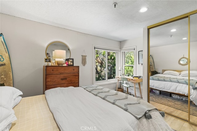 bedroom featuring a closet, wood finished floors, recessed lighting, and a textured ceiling