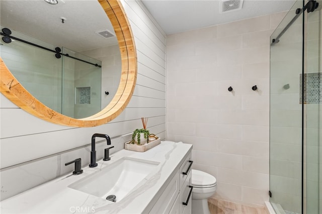 full bath featuring toilet, vanity, a stall shower, and visible vents