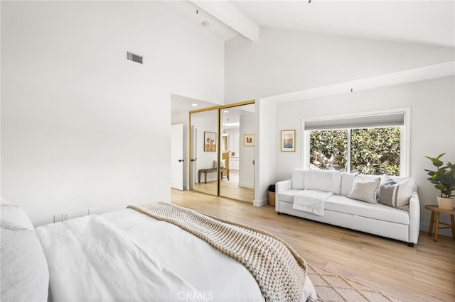 bedroom with high vaulted ceiling, visible vents, light wood-style floors, and beam ceiling