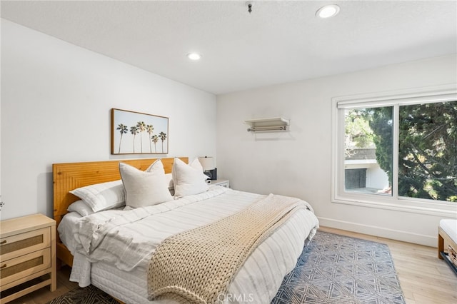 bedroom with baseboards, recessed lighting, and light wood-type flooring