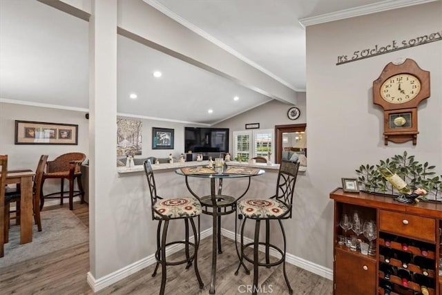 dining room with lofted ceiling with beams, wood finished floors, baseboards, ornamental molding, and recessed lighting