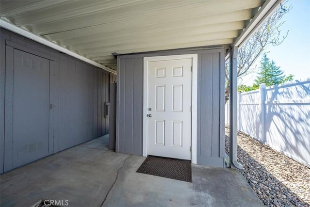 property entrance featuring an attached carport, fence, and visible vents