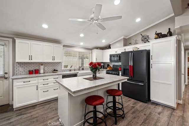 kitchen featuring vaulted ceiling, ornamental molding, ceiling fan, white cabinets, and black appliances