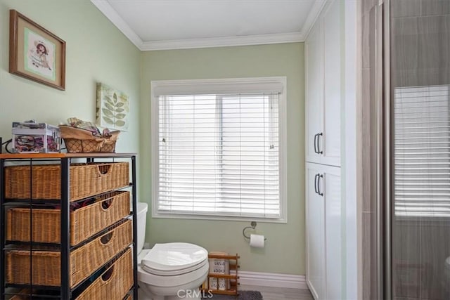 bathroom with baseboards, ornamental molding, and toilet