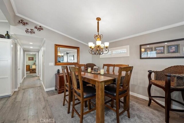 dining area with vaulted ceiling, wood finished floors, ornamental molding, and a chandelier