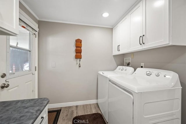 clothes washing area featuring washer and clothes dryer, crown molding, baseboards, light wood-style floors, and cabinet space