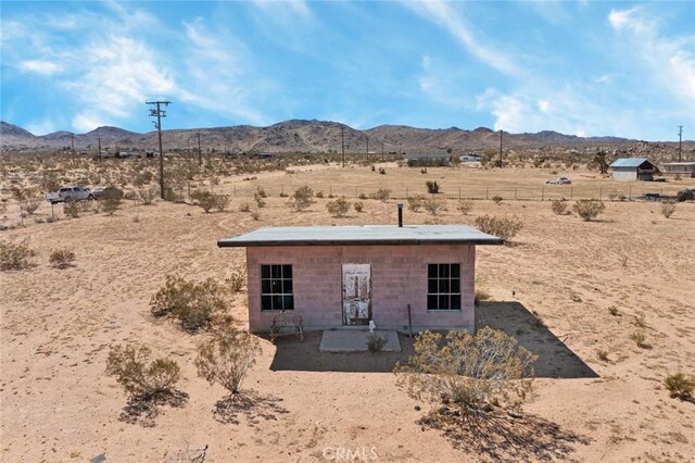 back of house with fence, a mountain view, a desert view, and a patio area
