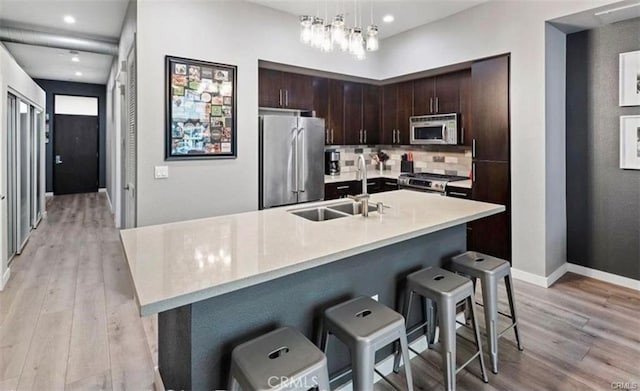 133 The Promenade N Unit 317, Long Beach, CA 90802 - kitchen featuring appliances with stainless steel finishes, a sink, light wood finished floors, dark brown cabinets, and light countertops