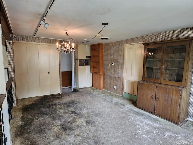 unfurnished dining area with visible vents, a chandelier, and unfinished concrete floors