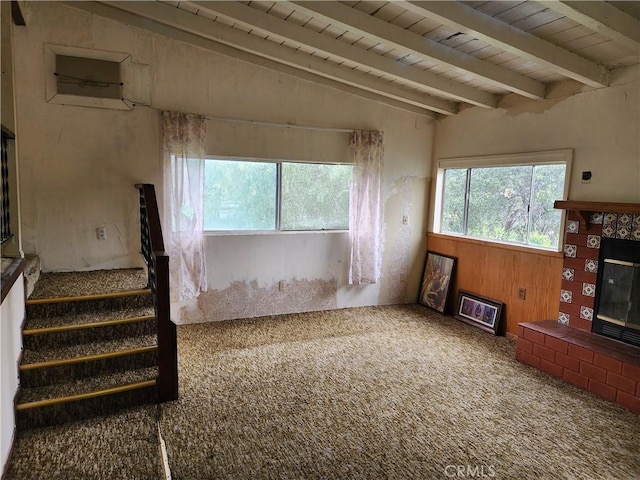 unfurnished living room with wooden ceiling, wood walls, a fireplace, and carpet floors
