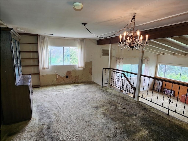 carpeted spare room featuring plenty of natural light and a chandelier