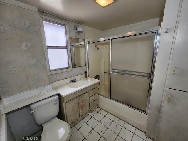 bathroom featuring toilet, enclosed tub / shower combo, vanity, and tile patterned flooring
