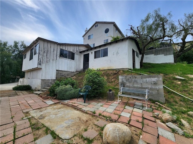rear view of house featuring board and batten siding and a patio