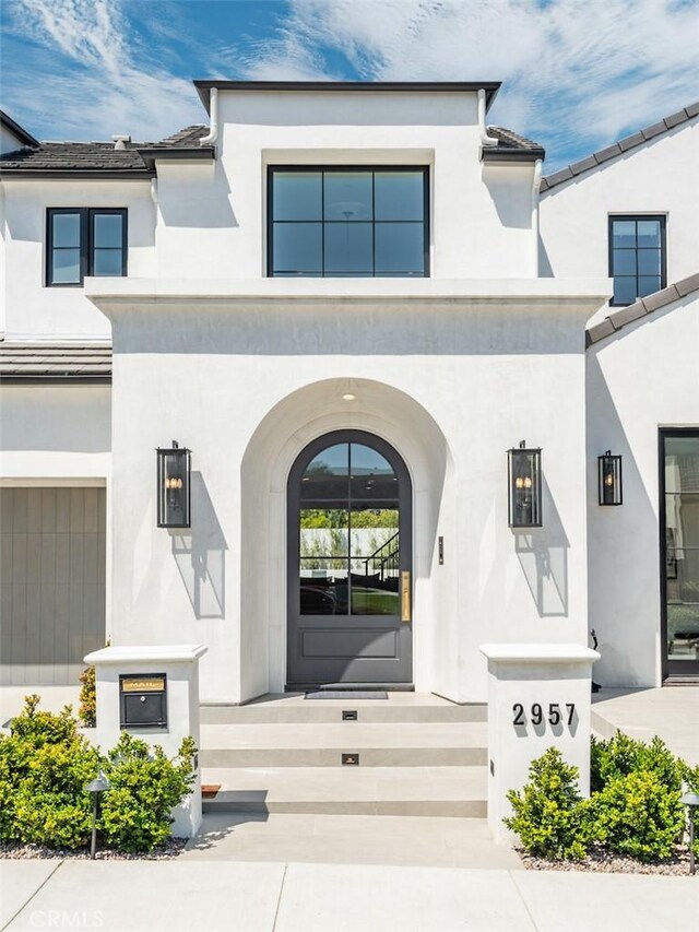 view of exterior entry featuring a garage and stucco siding