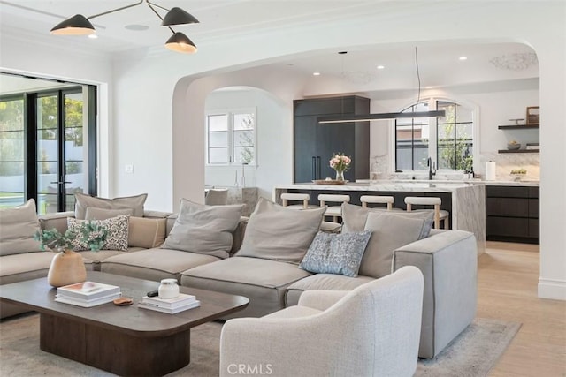 living area featuring plenty of natural light, arched walkways, recessed lighting, and light wood-style flooring