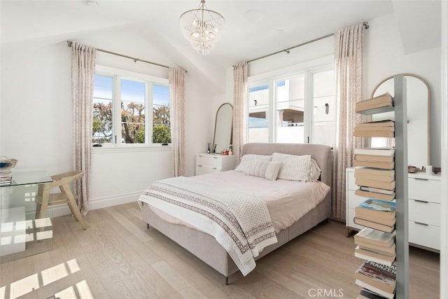 bedroom featuring baseboards, lofted ceiling, a chandelier, and light wood-style flooring