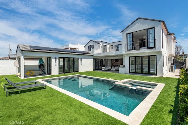 rear view of house with roof mounted solar panels, an outdoor hangout area, a balcony, stucco siding, and a lawn