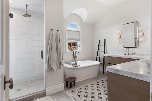 full bath with tile patterned flooring, a freestanding bath, vanity, baseboards, and a stall shower
