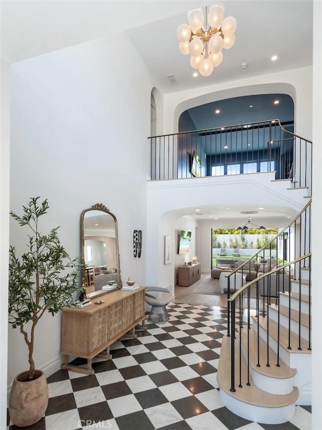entryway with arched walkways, stairway, a towering ceiling, and an inviting chandelier
