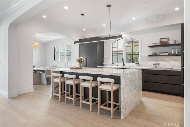 kitchen with modern cabinets, arched walkways, a healthy amount of sunlight, and a large island