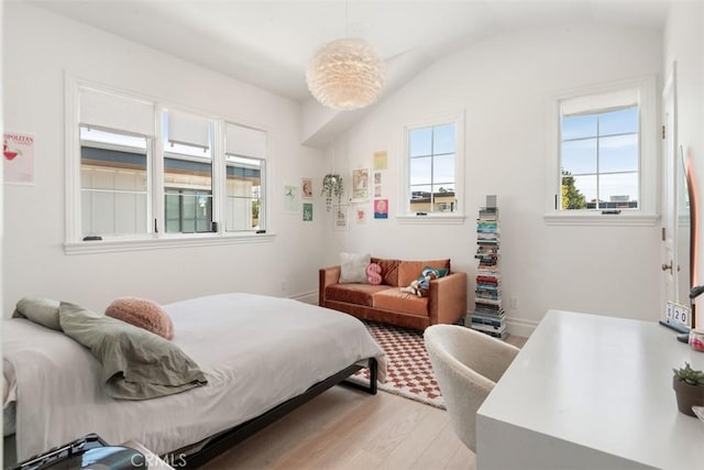bedroom featuring lofted ceiling, light wood-style flooring, and baseboards