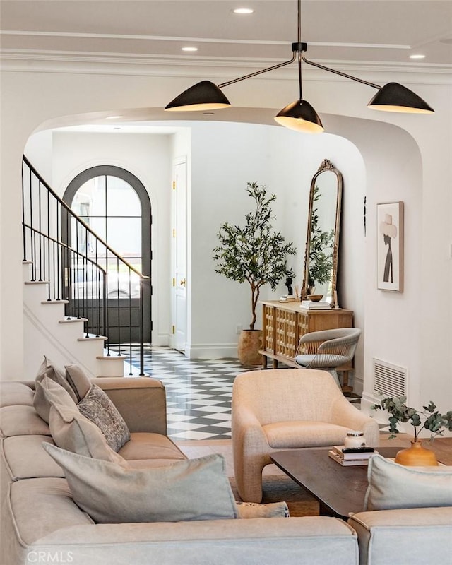 living area featuring tile patterned floors, arched walkways, baseboards, visible vents, and stairway