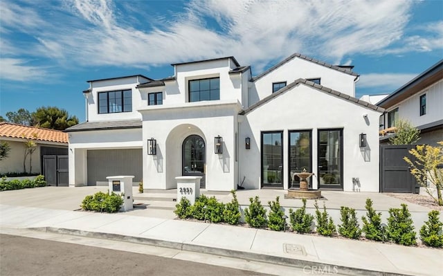 view of front of house with a gate, fence, concrete driveway, stucco siding, and a garage