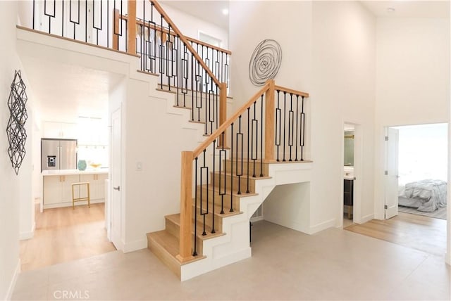 stairs featuring baseboards and a high ceiling