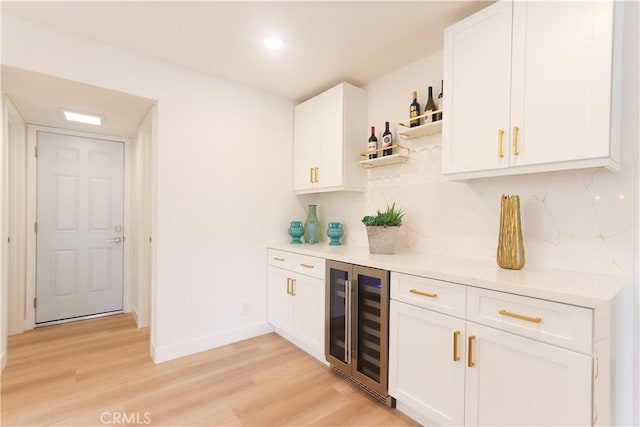 bar featuring a dry bar, beverage cooler, light wood-style flooring, recessed lighting, and baseboards