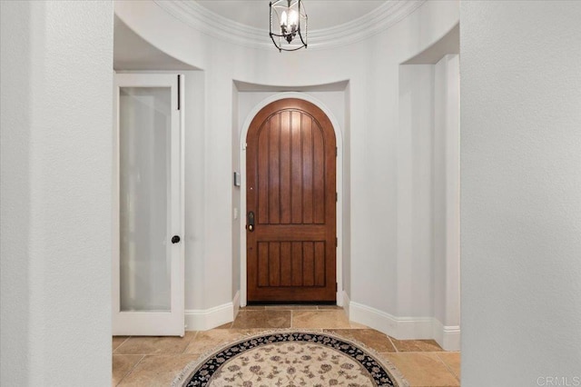 entrance foyer featuring baseboards, arched walkways, a notable chandelier, and stone tile floors