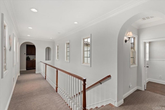 hallway featuring arched walkways, light colored carpet, crown molding, and recessed lighting