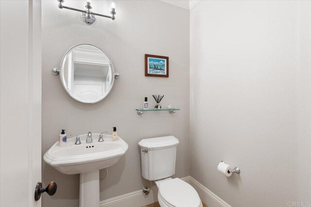 half bath featuring toilet and baseboards