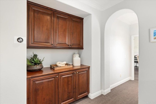 hall featuring arched walkways, carpet flooring, baseboards, and ornamental molding