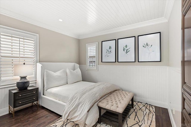 bedroom with dark wood-style floors, crown molding, and a wainscoted wall
