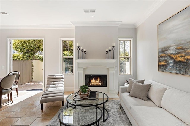living area featuring a wealth of natural light, a glass covered fireplace, visible vents, and crown molding